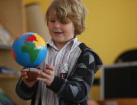 Ein Kind in der Schule untersucht aufgeregt einen Globus